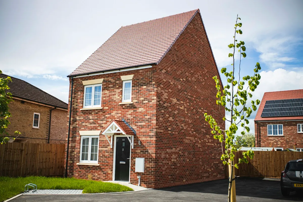 Modern red-brick detached new-build house with a pitched roof, front lawn and driveway
